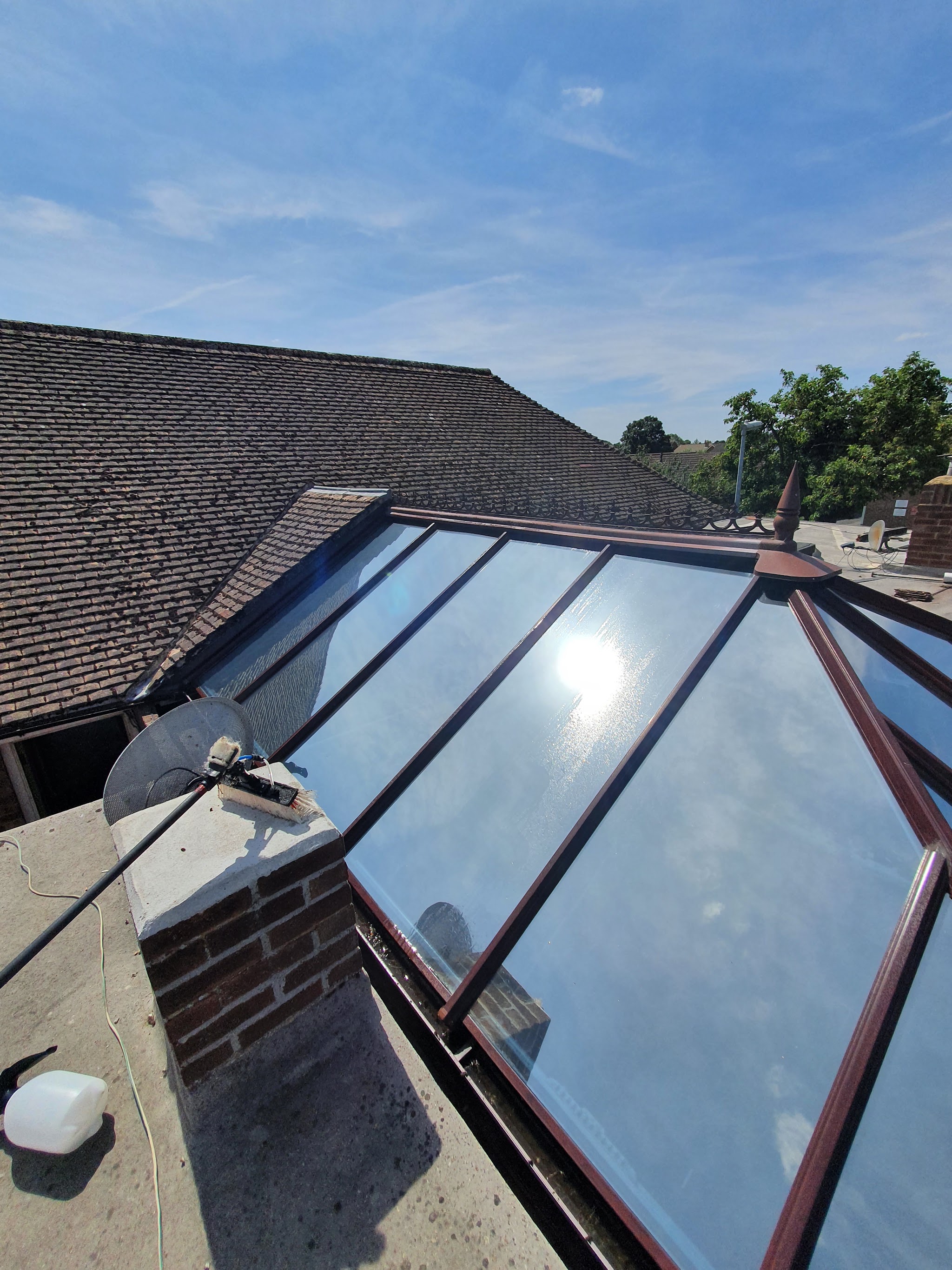 Cleaning a conservatory glass roof with a brush on a water-fed pole