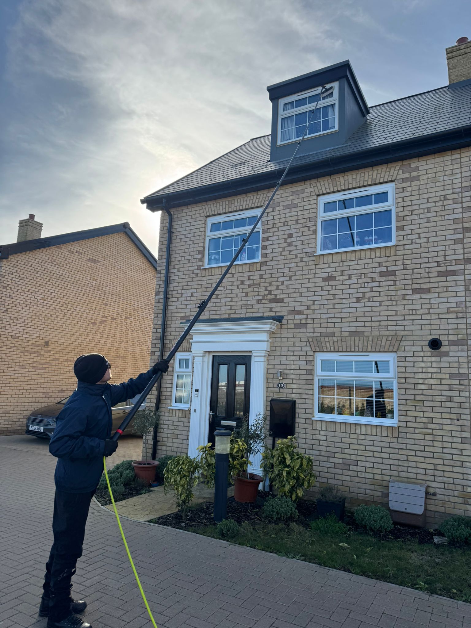 Cleaning the upper windows of a three-storey townhouse with a water-fed pole