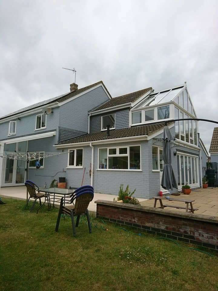 A grey-clad house with a conservatory and garden patio